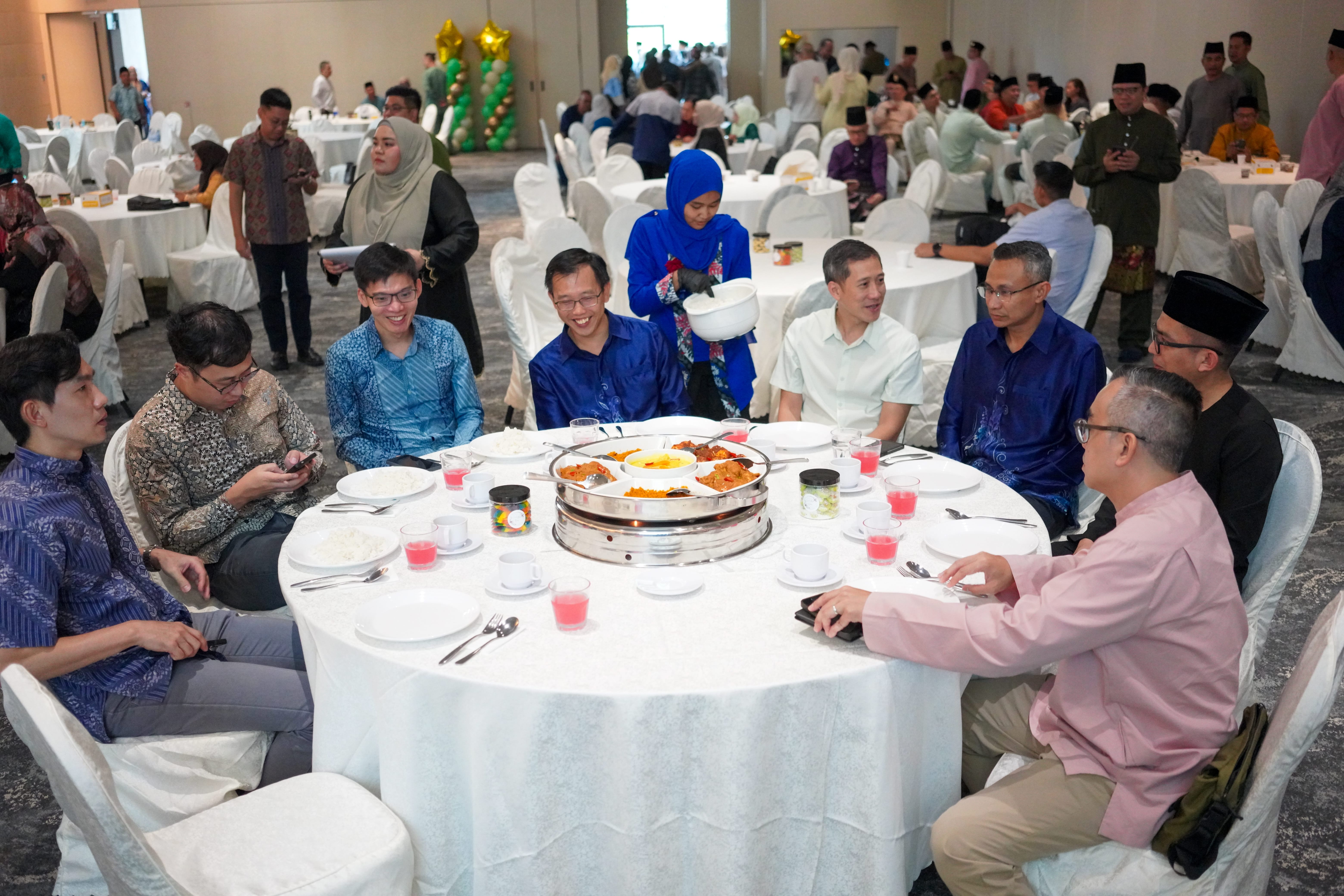 Attendees seated around a round banquet table while refreshments are being served.